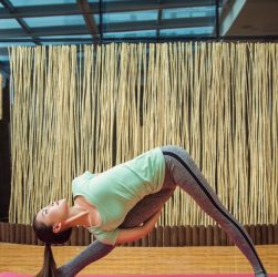 woman in green tank top and gray leggings doing yoga